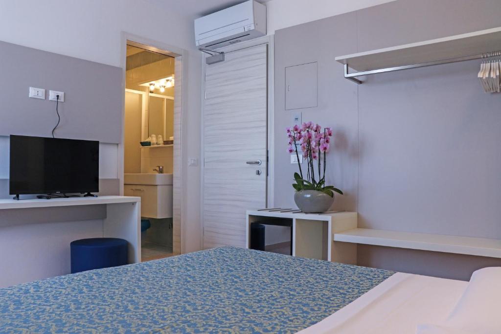 une chambre avec un lit et une table avec un vase de fleurs dans l'établissement Hotel Principe, à Caorle