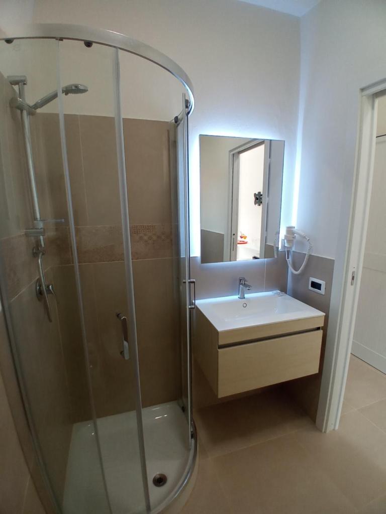 une salle de bains avec douche, lavabo et miroir dans l'établissement Il Calabriano Residence, à Zambrone