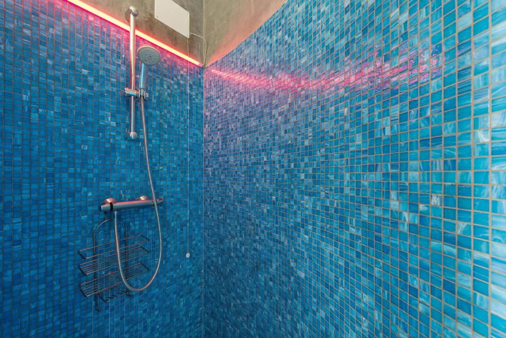 La salle de bains est pourvue d'une douche carrelée de bleu avec un tuyau. dans l'établissement Golfo di Venere, à Lenno 20 autres photos