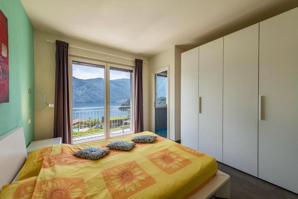 une chambre avec un lit et une grande fenêtre dans l'établissement Golfo di Venere, à Lenno