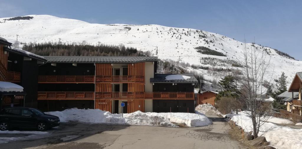 un bâtiment avec une montagne enneigée en arrière-plan dans l'établissement Studio 2 alpes, proche lac buissonnière, ménage inclus, balcon, parking, à Les Deux Alpes