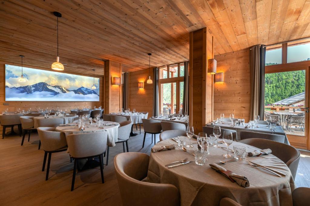 une salle à manger avec tables, chaises et fenêtres dans l'établissement Le Chalet Blanc Hôtel & Spa, à Montgenèvre