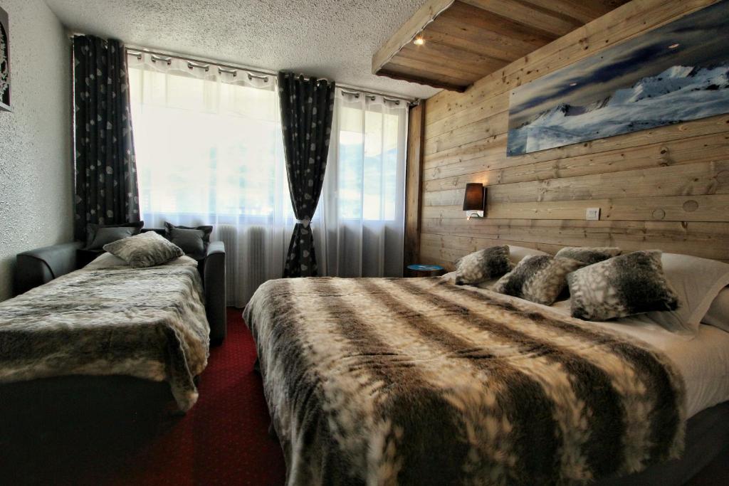 une chambre d'hôtel avec deux lits et une fenêtre dans l'établissement Hotel Le Pelvoux, aux Menuires