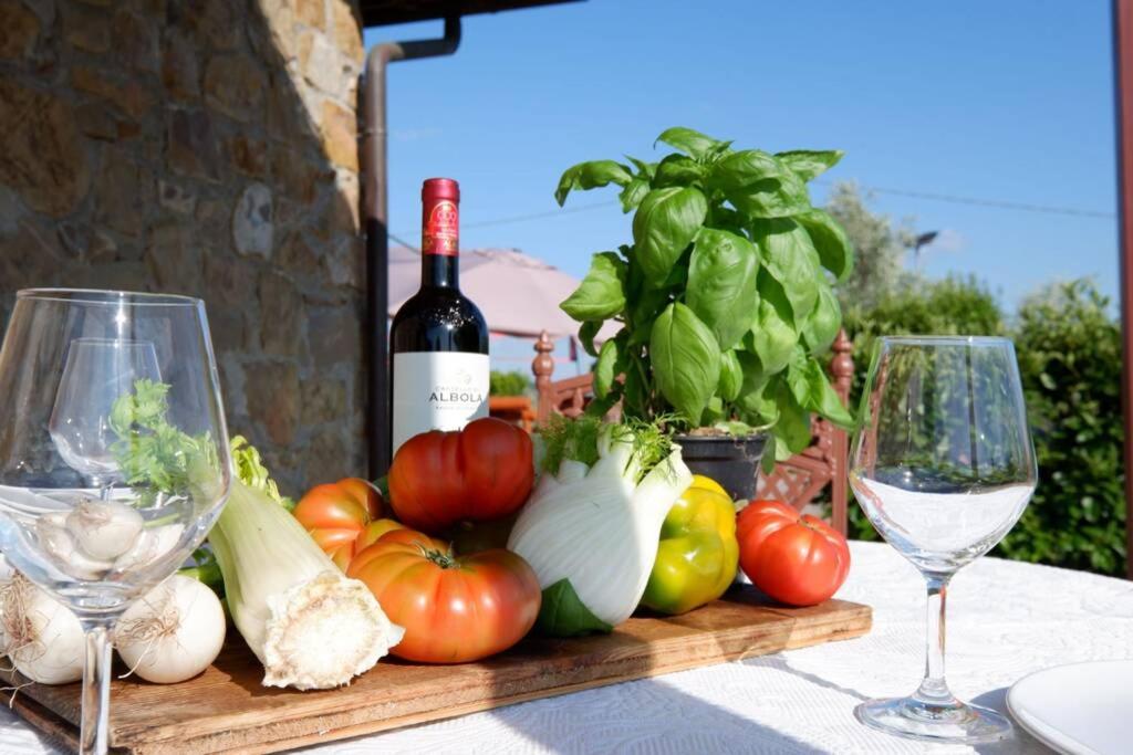 - une table avec un bouquet de légumes et des verres à vin dans l'établissement Il Villino del Daino - Toscana, à Loro Ciuffenna