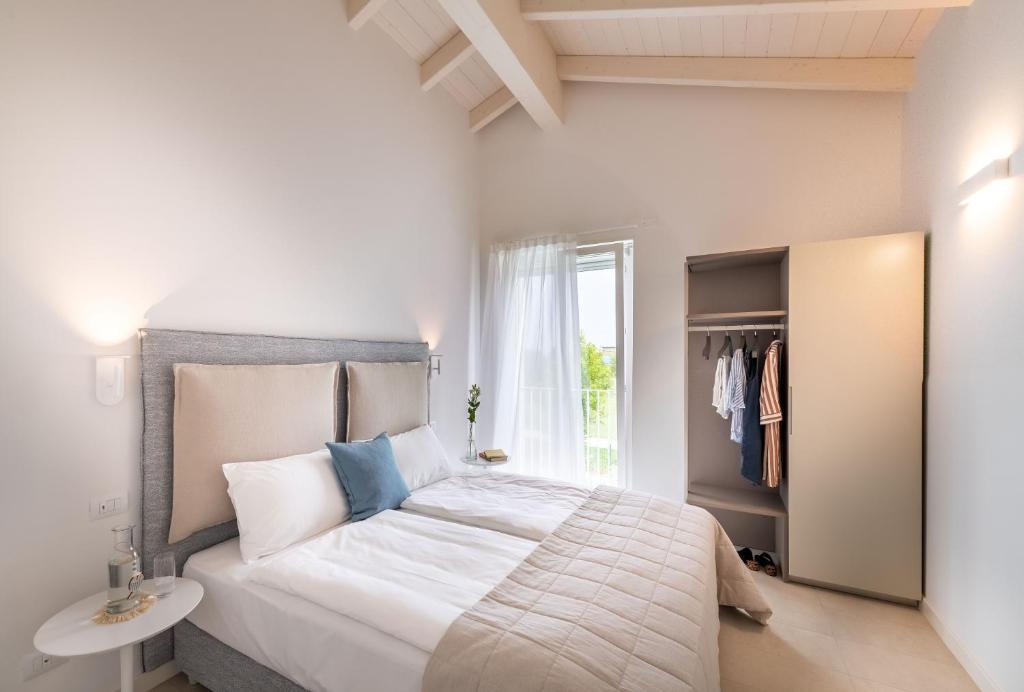 une chambre avec un grand lit blanc et une fenêtre dans l'établissement Pareus Beach Resort, à Caorle 38 autres photos