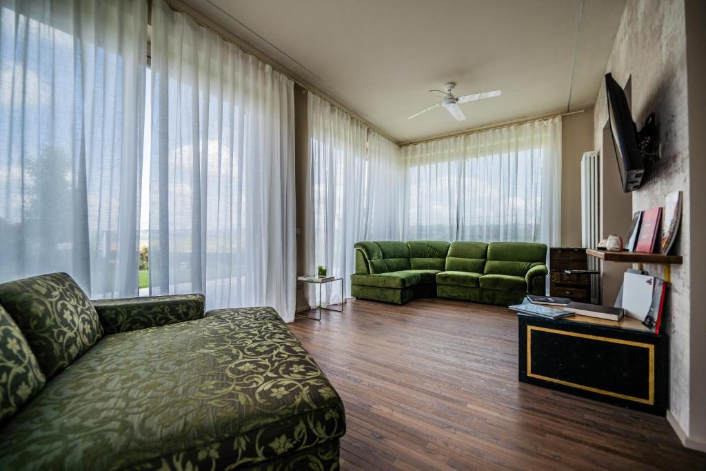 Elle comprend un salon doté d'un mobilier vert et de grandes fenêtres. dans l'établissement Villa Leolo' Monforte d'Alba, à Monforte dʼAlba