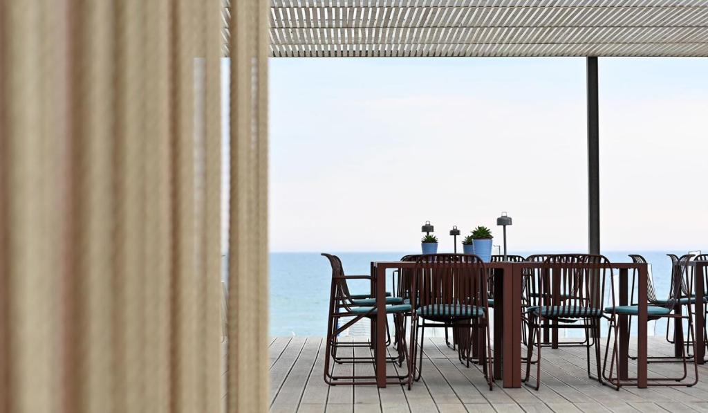 une table et des chaises sur un balcon avec l'océan dans l'établissement Hotel Royal Paestum, à Paestum