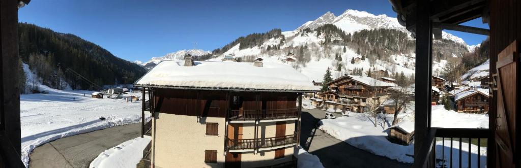 un bâtiment avec de la neige sur le toit d'une montagne dans l'établissement Le Croisse Baulet, à La Giettaz