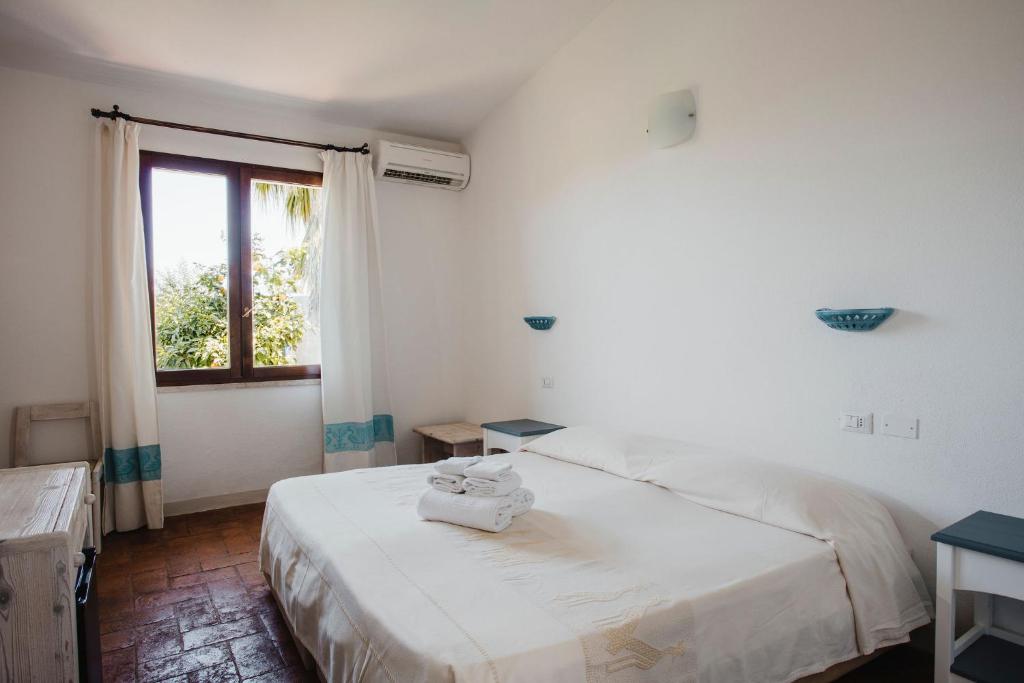 une chambre blanche avec un lit et une fenêtre dans l'établissement Resort Fior di Sardegna, à Posada 76 autres photos