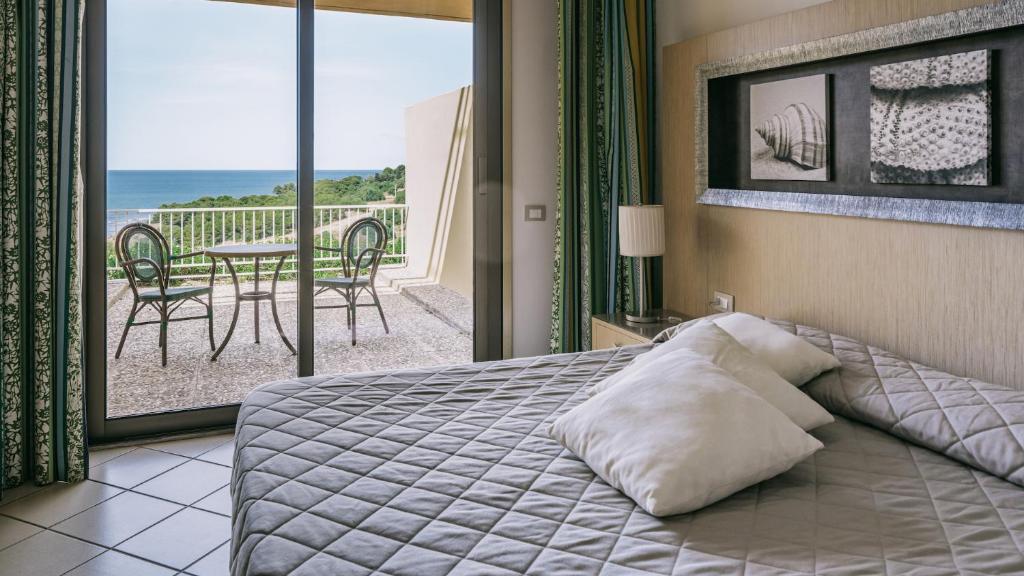 une chambre avec un lit et un balcon avec une table dans l'établissement MClub Cala Regina, à Sciacca