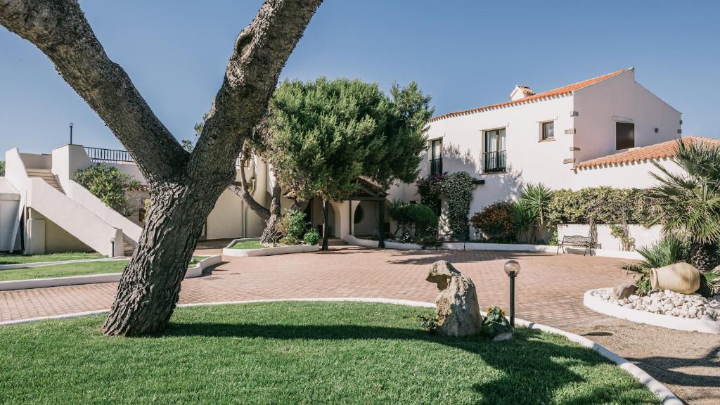 une maison avec un arbre au milieu d'une cour dans l'établissement MClub Del Golfo, à Sorso