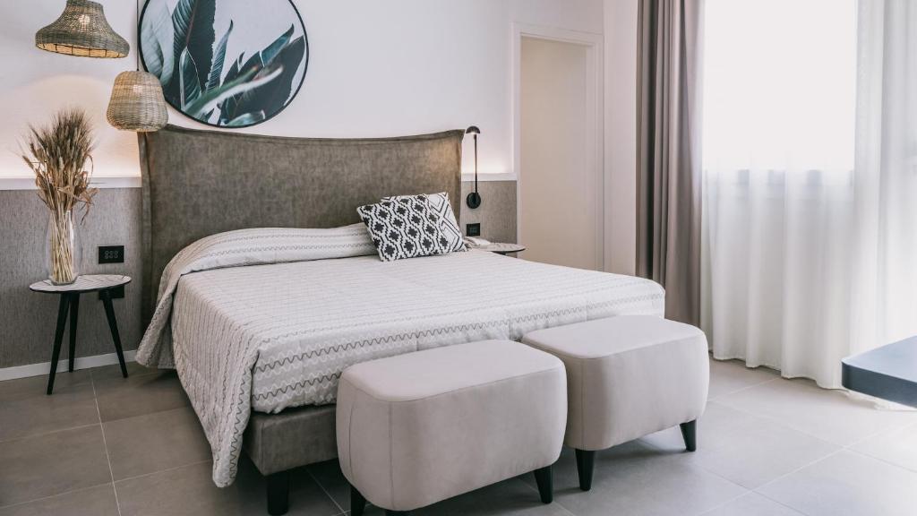 - une chambre avec un lit et deux tabourets blancs dans l'établissement Mangia's Himera Resort, à Campofelice di Roccella