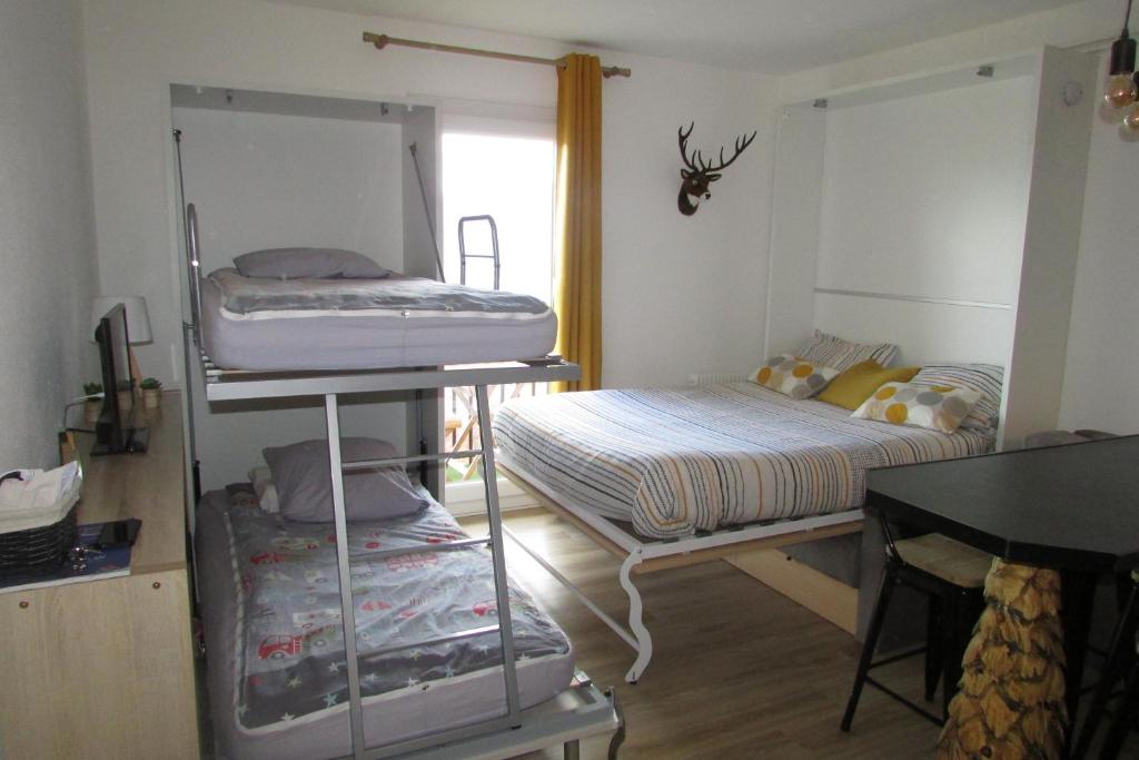 une chambre avec deux lits superposés et un bureau dans l'établissement Superbe studio Les Angles, aux Angles