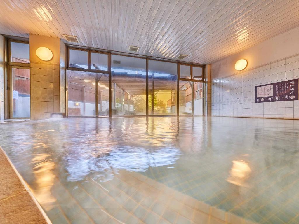 une piscine vide dans un bâtiment avec des portes en verre dans l'établissement Ooedo Onsen Monogatari Ureshinokan, à Ureshino