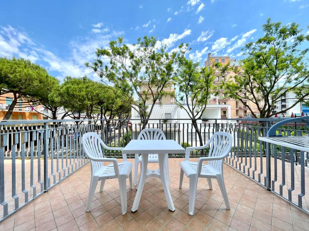 d'une table blanche et de trois chaises sur la terrasse. dans l'établissement Hotel Trovatore, à Lido di Jesolo