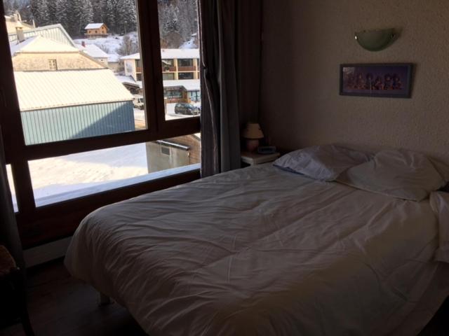 une chambre avec un lit et une grande fenêtre dans l'établissement APPARTEMENT DE MONTAGNE, à Mijoux