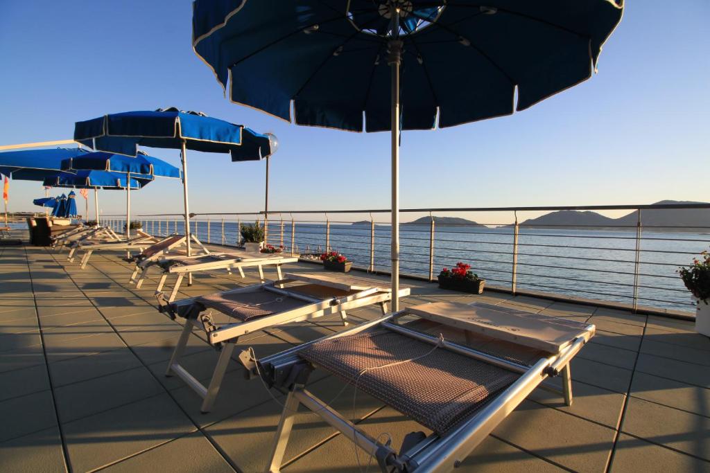 une rangée de tables avec parasols sur une terrasse dans l'établissement Hotel San Terenzo, à Lerici
