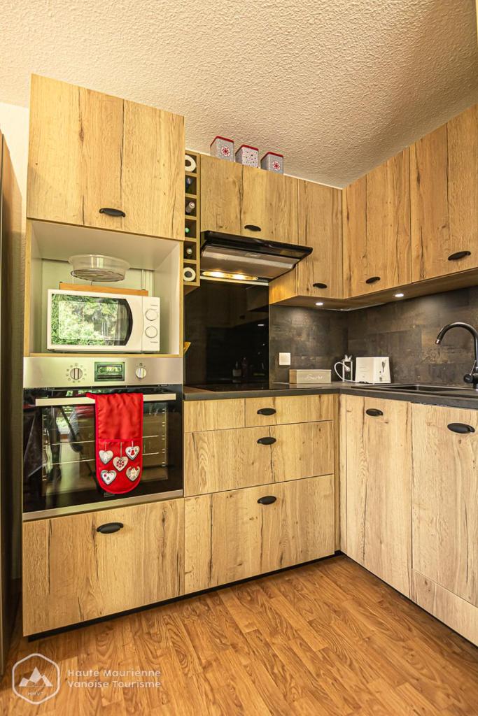 - une cuisine avec des placards en bois et un four micro-ondes dans l'établissement Le chalet d'Isis - La Norma, à Villarodin-Bourget