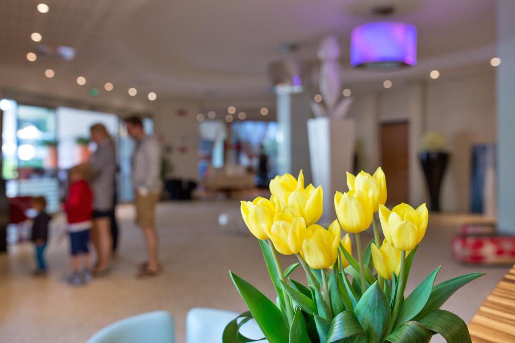 un bouquet de tulipes jaunes dans un vase sur une table dans l'établissement Bibione Palace Hotel, à Bibione