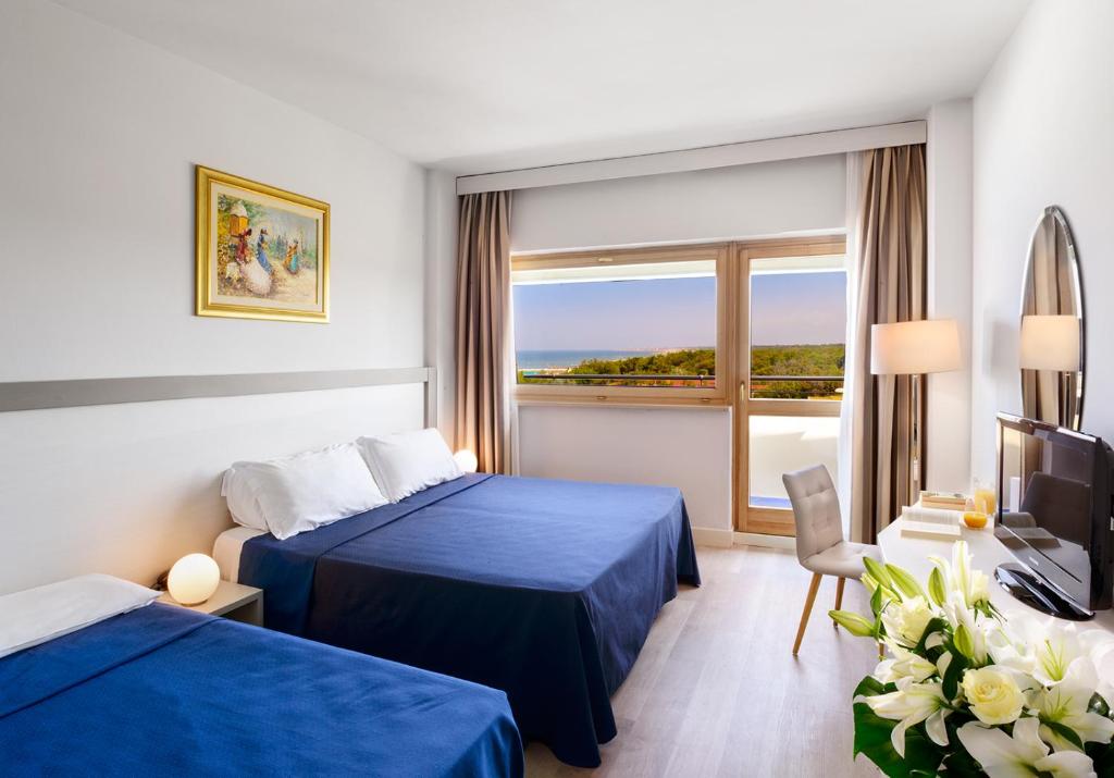 une chambre d'hôtel avec deux lits et une fenêtre dans l'établissement Grand Hotel Continental, à Tirrenia