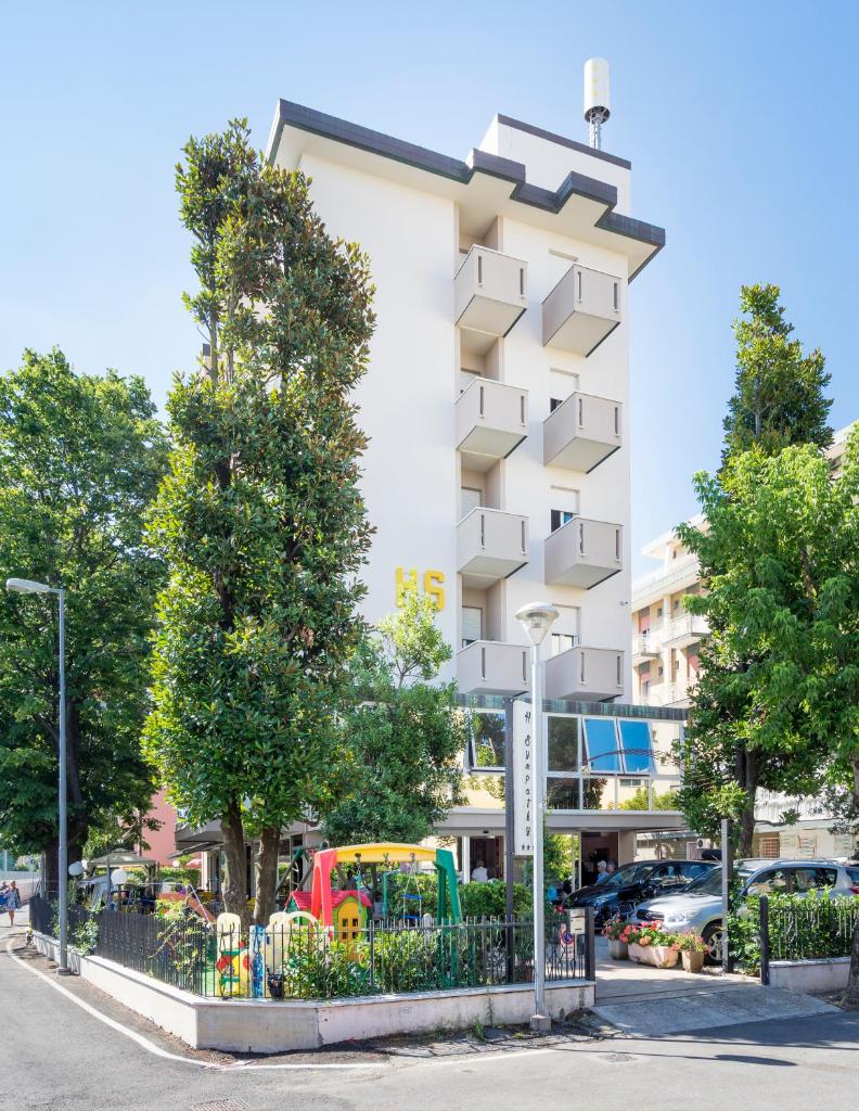 un bâtiment blanc avec des arbres devant dans l'établissement Hotel Sympathy, à Rimini