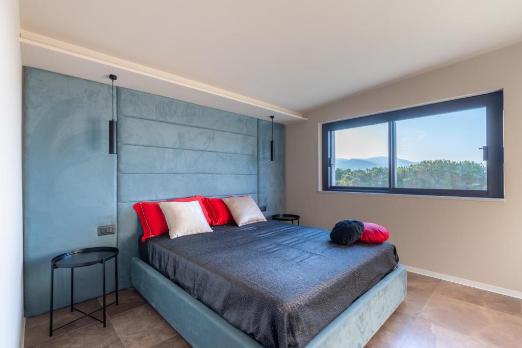 une chambre avec un lit avec des oreillers rouges et une fenêtre dans l'établissement Villa vista mare con piscina a sfioro a Scopello, à Castellammare del Golfo