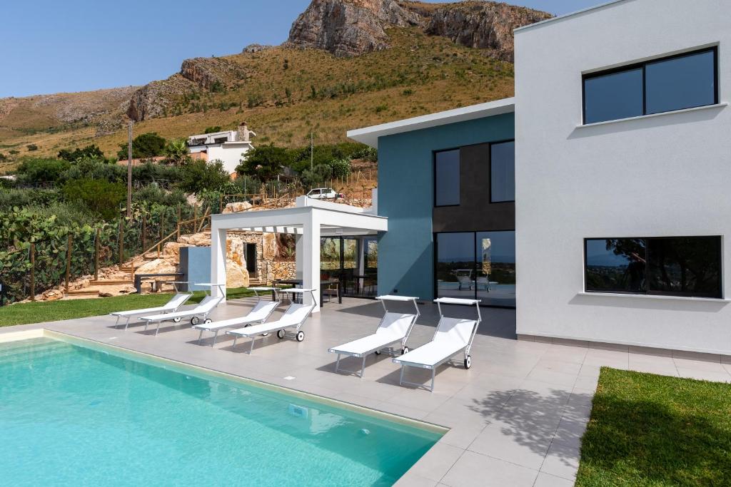 une maison avec une piscine et des chaises blanches dans l'établissement Villa vista mare con piscina a sfioro a Scopello, à Castellammare del Golfo