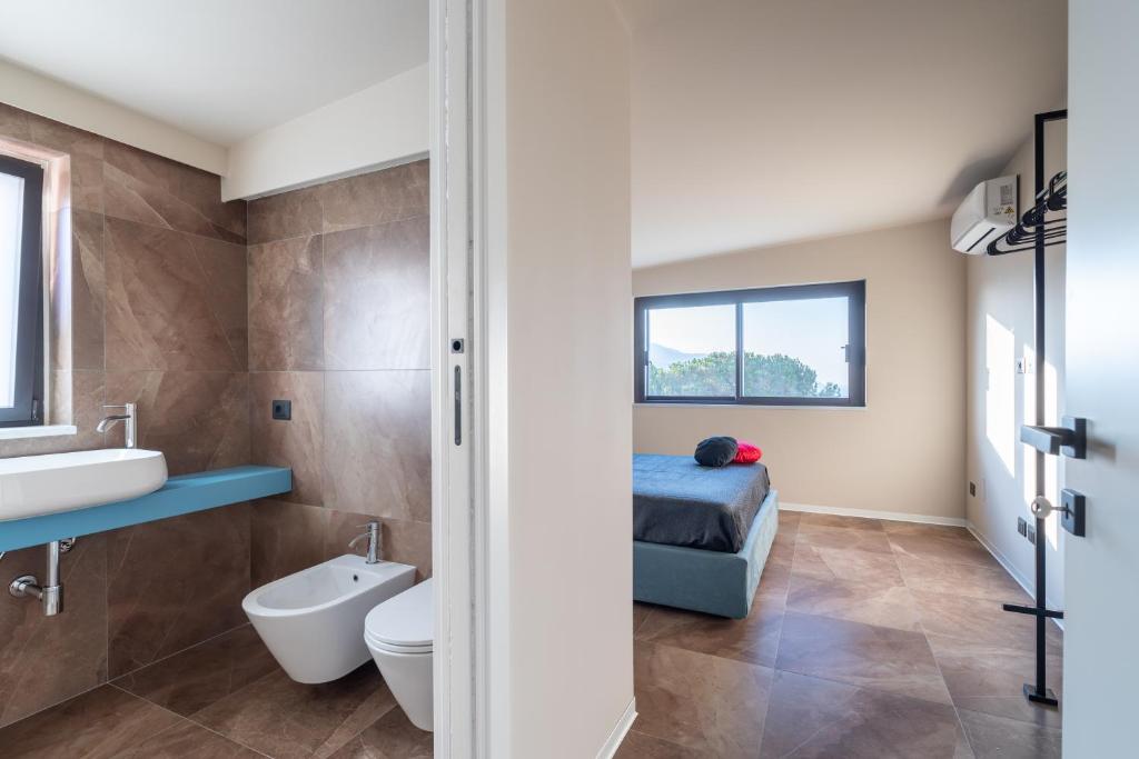 une salle de bain avec toilettes et lavabo et un lit dans l'établissement Villa vista mare con piscina a sfioro a Scopello, à Castellammare del Golfo 13 autres photos