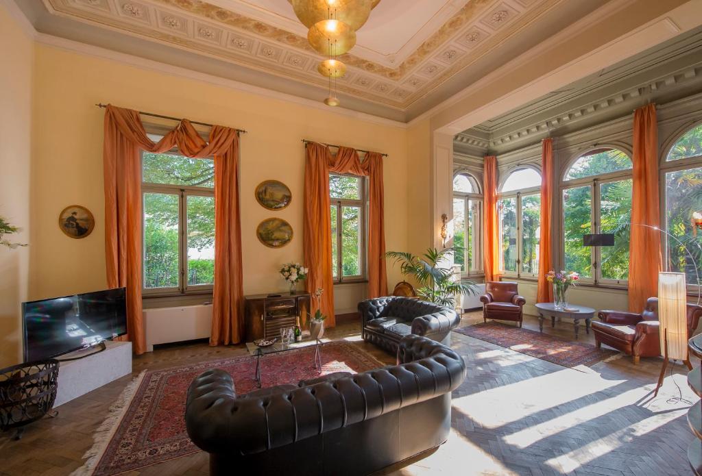 - un salon avec des meubles en cuir et des fenêtres dans l'établissement Villa Confalonieri, à Mandello del Lario