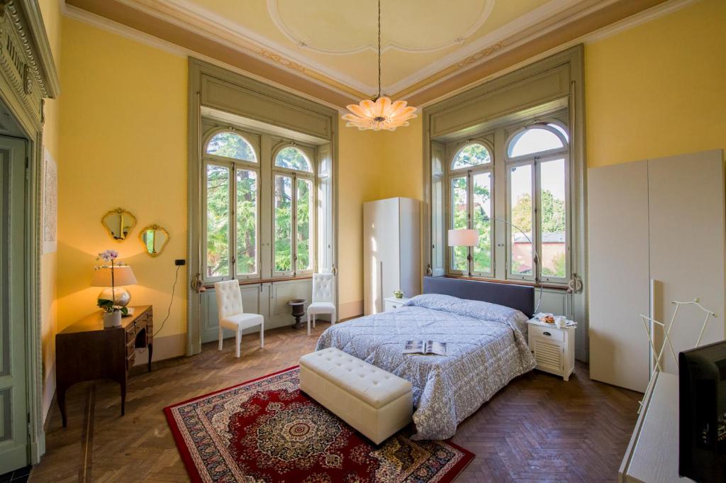 - une chambre avec des murs jaunes, un lit et des fenêtres dans l'établissement Villa Confalonieri, à Mandello del Lario