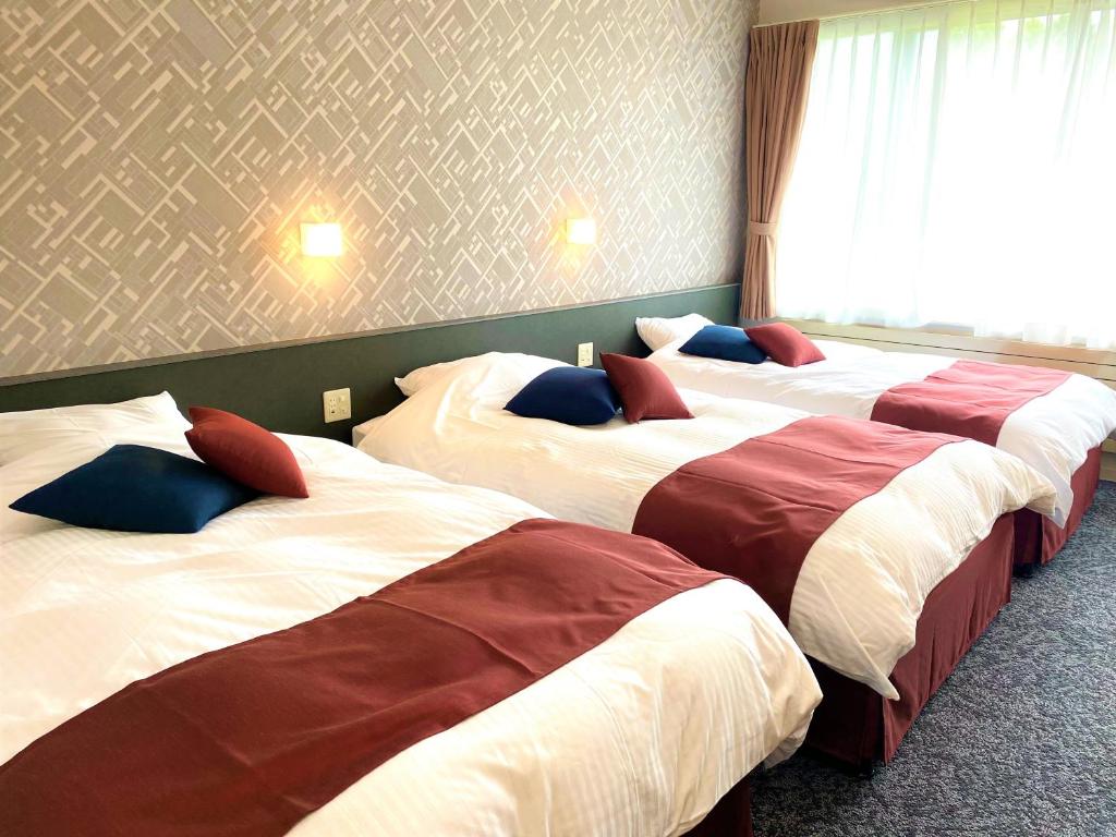 une chambre d'hôtel avec trois lits dans une chambre dans l'établissement Tokachi Nauman Onsen Hotel arco, à Makubetsu 37 autres photos