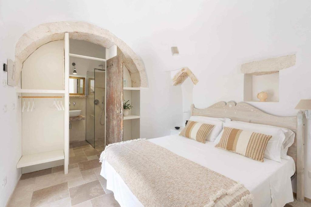 une chambre blanche avec un lit et une salle de bain dans l'établissement Trullo Juno, à Ostuni