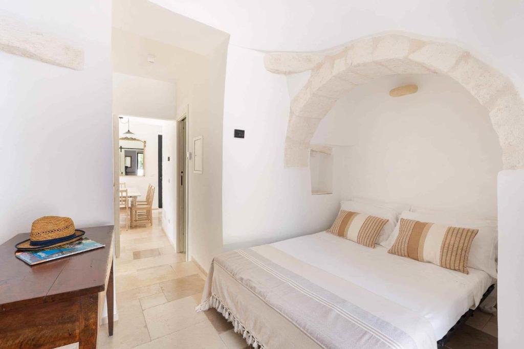 une chambre blanche avec un lit et une table dans l'établissement Trullo Juno, à Ostuni