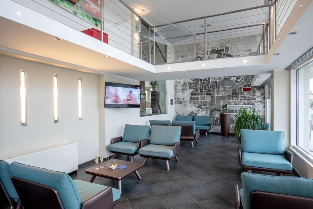 une salle d'attente avec des chaises bleues et une table dans l'établissement Hotel Miramare, à Latina