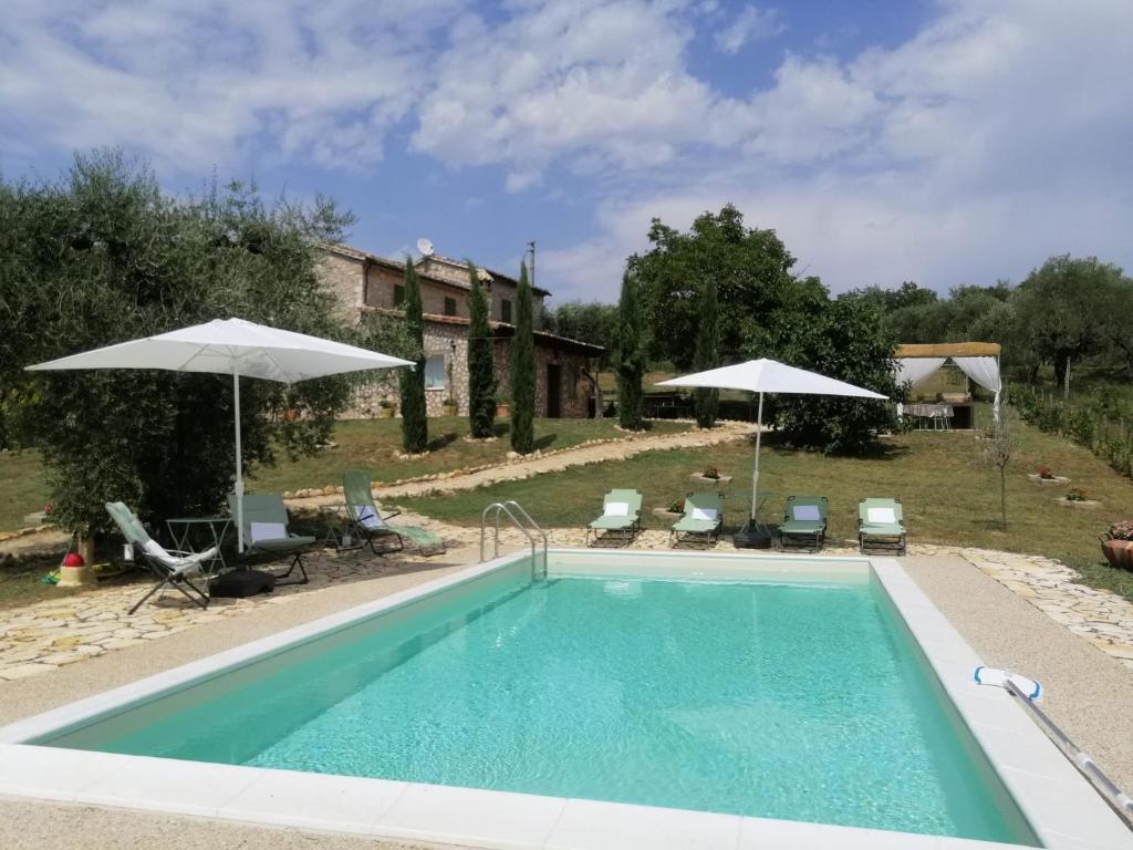 une piscine avec deux parasols et une maison dans l'établissement sacrobosco Country House, à Porchiano