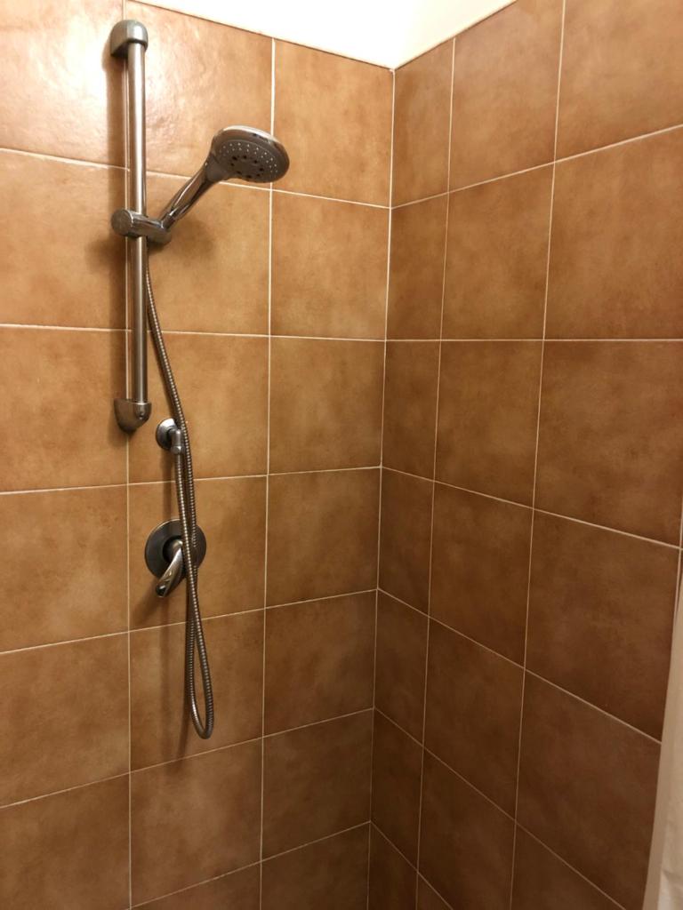 une douche avec une pomme de douche sur un mur carrelé dans l'établissement Tiglio Vieste, à Vieste 86 autres photos