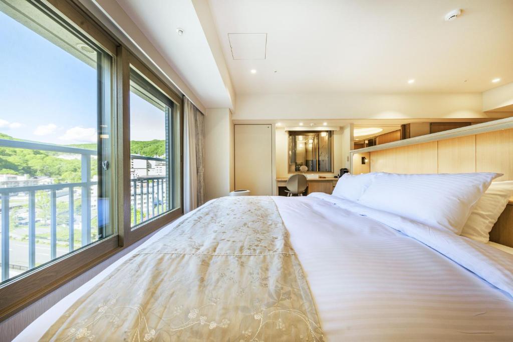 une chambre avec un grand lit avec une grande fenêtre dans l'établissement Hotel Mahoroba, à Noboribetsu