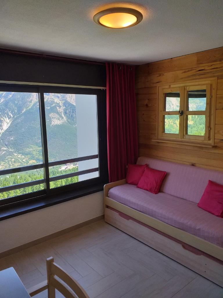 Cette chambre dispose d'un canapé et de fenêtres. dans l'établissement La Voile - Pendine 2 - Puy Saint Vincent - Hautes Alpes, à Puy-Saint-Vincent
