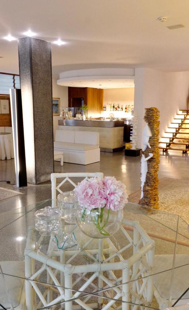 un vase de fleurs sur une table en verre dans un hall dans l'établissement Hotel Pinocchio, à Cattolica