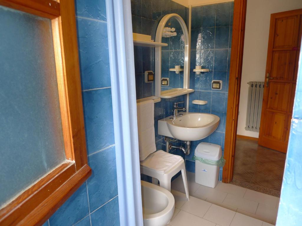 La salle de bains est pourvue de carrelage bleu, d'un lavabo et de toilettes. dans l'établissement Hotel Alexander, à Tropea 70 autres photos