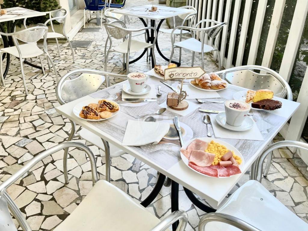 une table blanche avec des assiettes de nourriture dessus dans l'établissement Hotel Niagara Riccione, à Riccione 75 autres photos