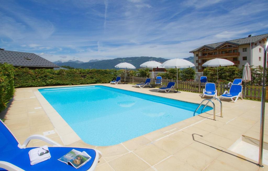 une piscine avec des chaises bleues et des parasols dans l'établissement Résidence Odalys Le Buet, à Morillon