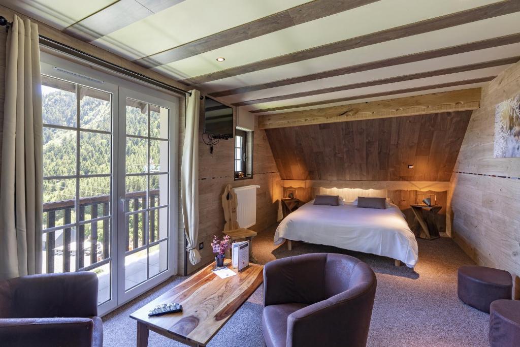 une chambre avec un lit et une grande fenêtre dans l'établissement La Sapinière, à Saint-Lary-Soulan