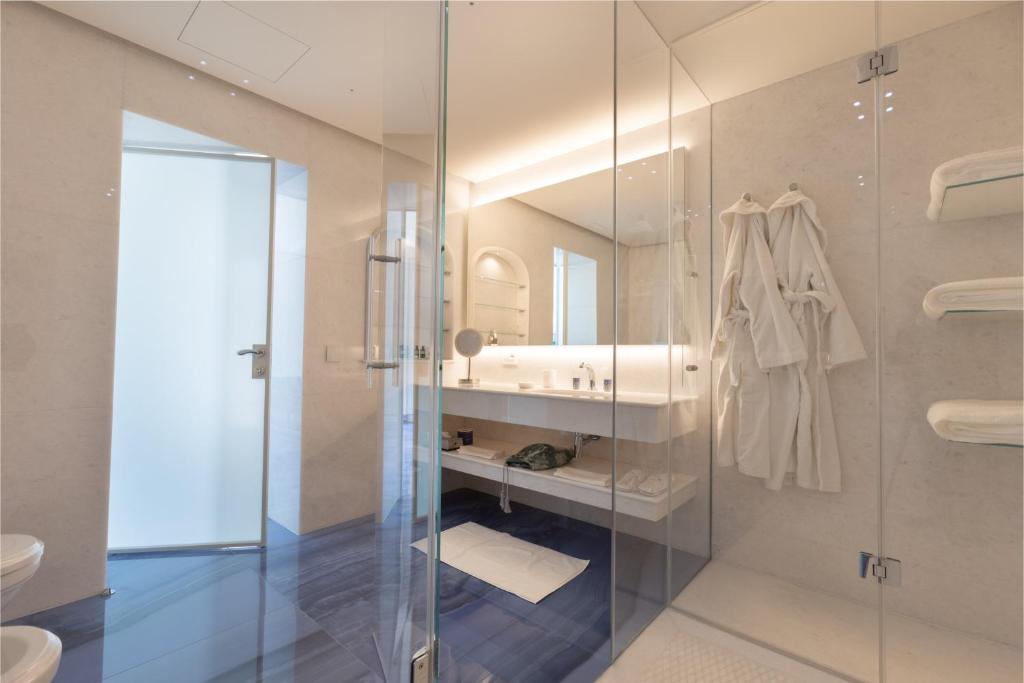 une salle de bain avec une douche en verre et un lavabo dans l'établissement Grotta Palazzese Beach Hotel, à Polignano a Mare 116 autres photos