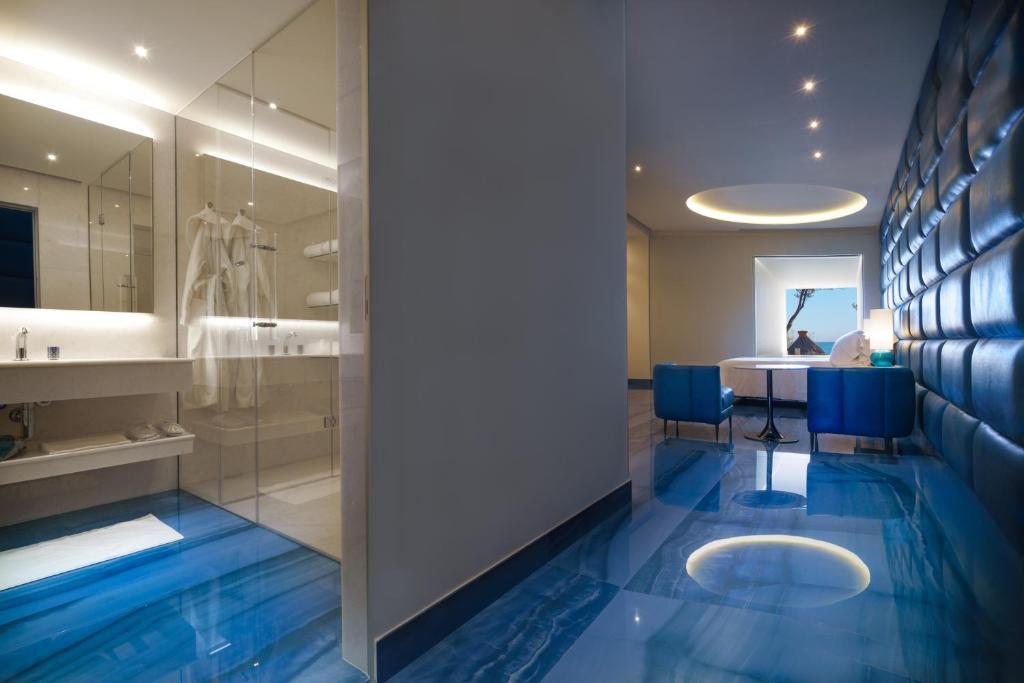 une salle de bain avec un sol bleu et une table et des chaises dans l'établissement Grotta Palazzese Beach Hotel, à Polignano a Mare