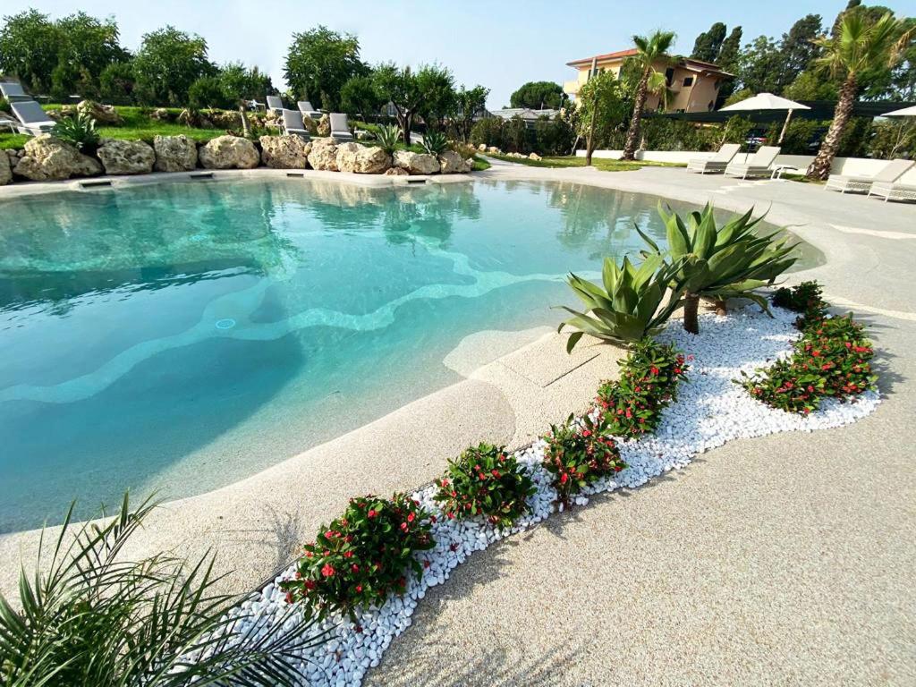une grande piscine avec quelques plantes et fleurs dans l'établissement Suite Hotel L'Oasi di Riaci, à Santa Domenica