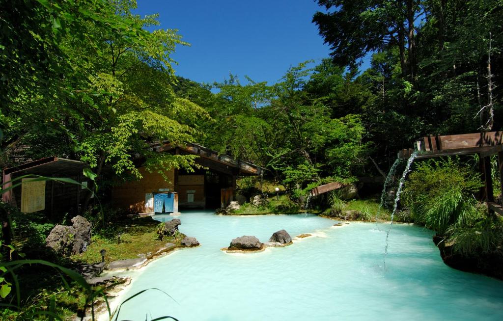 un bassin d'eau bleue avec des rochers et des arbres dans l'établissement Awanoyu, à Matsumoto