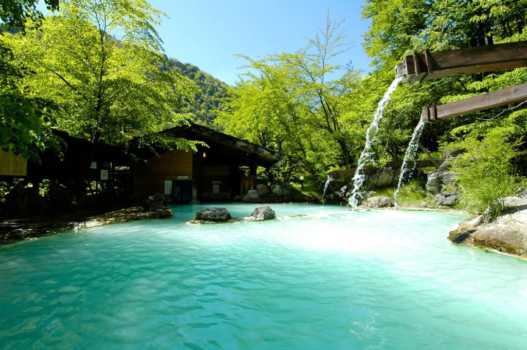 une piscine d'eau bleue avec une cascade dans l'établissement Awanoyu, à Matsumoto 37 autres photos
