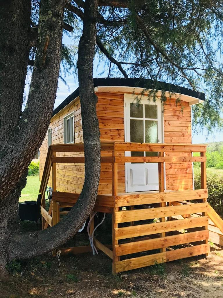 une cabane en rondins avec un grand arbre dans l'établissement ROULOTTE DE CHARME, à Saint-Genest-de-Bauzon