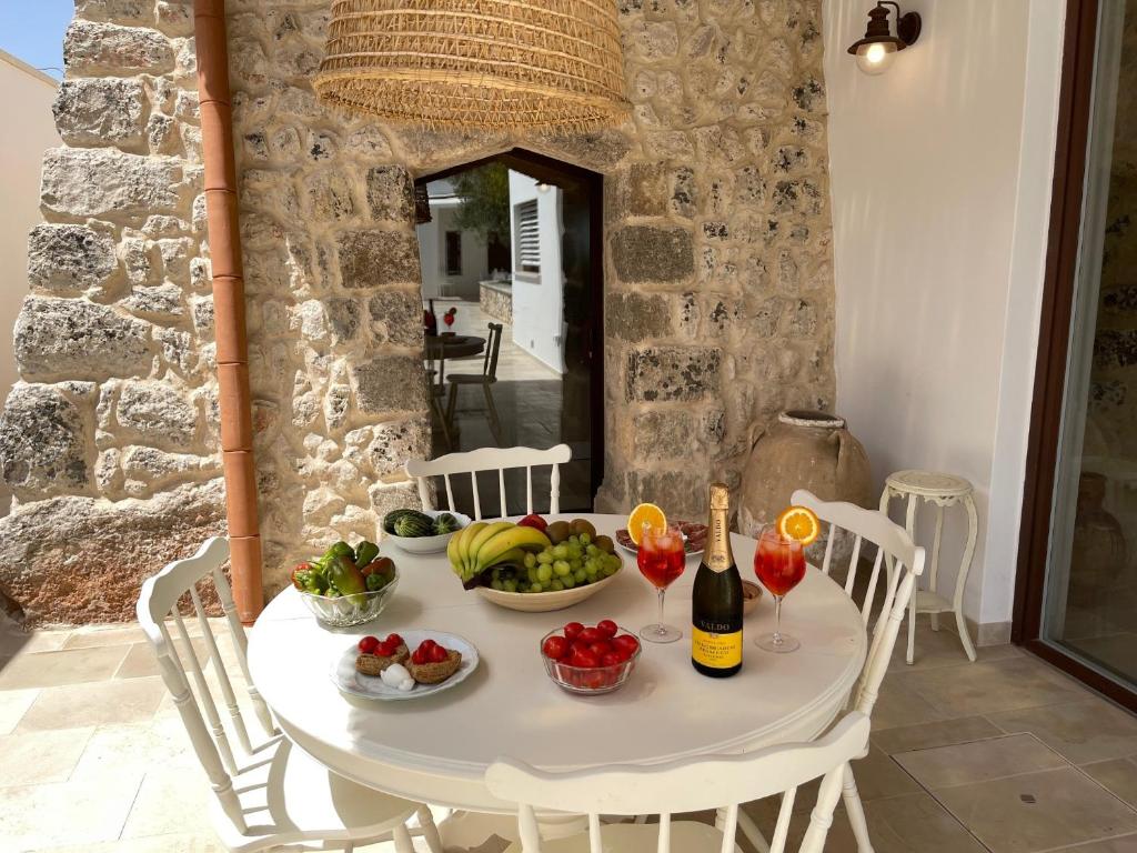 - une table blanche avec des fruits et des bouteilles de vin dans l'établissement Le Liame Antico Trullo, à Gagliano del Capo